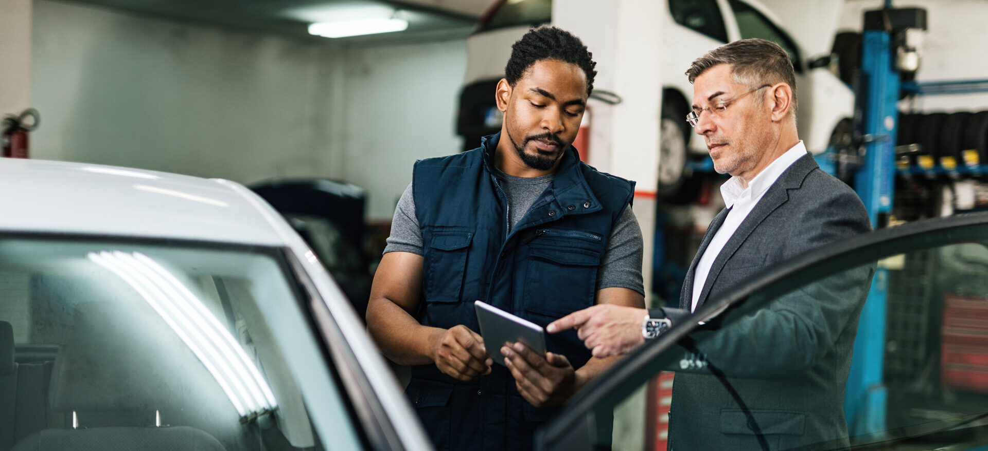 A mechanic showing a customer information about a car on a tablet