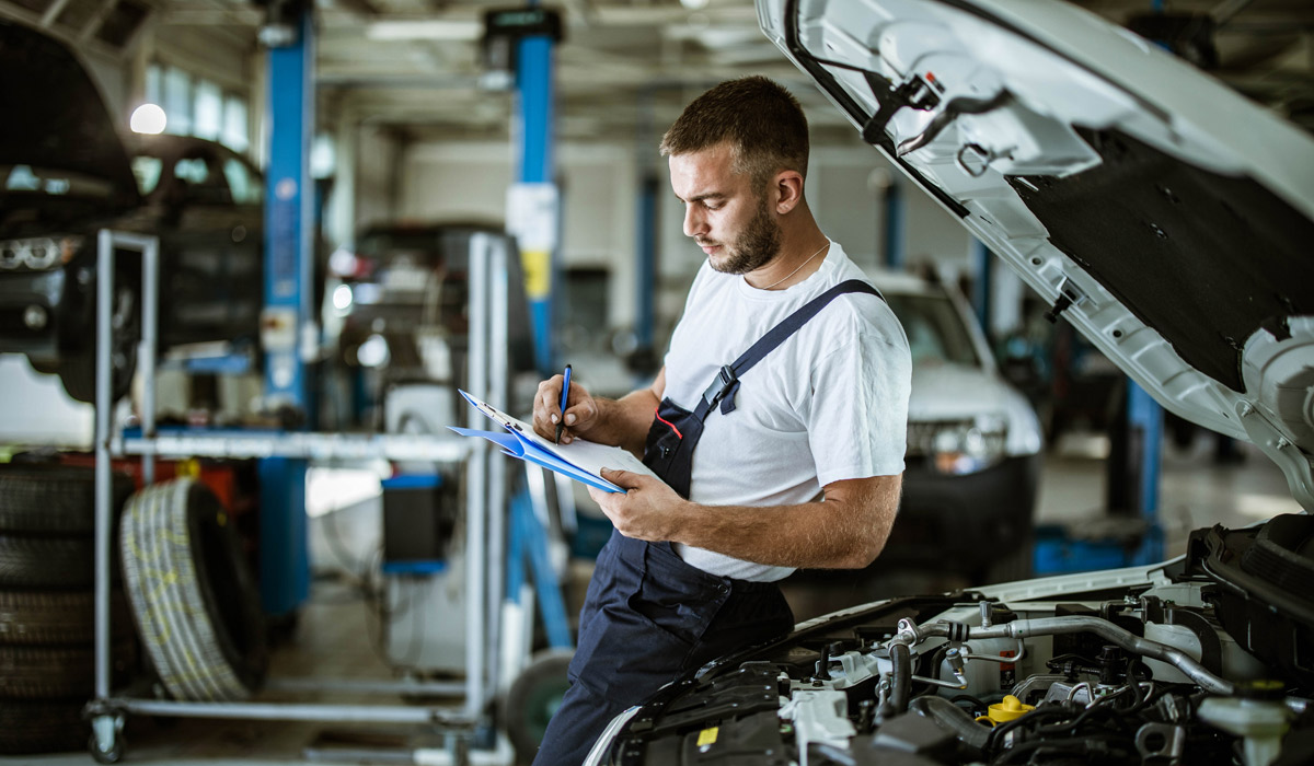 Mechanic writing down information on a clipboard in vehicle repair shop